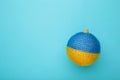 Glass Christmas ball toy on blue background with the flag of Ukraine Royalty Free Stock Photo