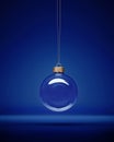 Glass christmas bauble hanging in front of luxury dark blue background