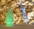 A glass Christmas toy, a green Christmas tree on a golden blurred background