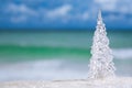 Glass christmas tree on beach with seascape background