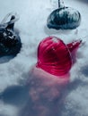 Glass, Christmas tree toys lying on the snow are covered with snowflakes, illuminated by the evening light. Royalty Free Stock Photo