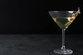 Glass of Classic Dry Martini with olives on table against black background. Space for text Royalty Free Stock Photo