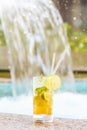 Glass of classic mojito cocktail with caipirinha on stone edge of swimming pool. Royalty Free Stock Photo