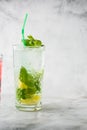Glass with classic mojito cocktail with lemon and mint, cold refreshing drink or beverage with ice on bright marble background. Royalty Free Stock Photo