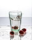 In the glass with clean and transparent water, falls fresh strawberries, splashes water.