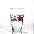 In the glass with clean and transparent water, falls fresh strawberries, splashes water.