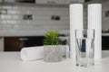 A glass of clean water with osmosis filter and cartridges on white table in a kitchen interior. Concept Household filtration Royalty Free Stock Photo