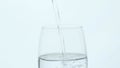 A glass of clean water on a white background close-up. Water is pouring into a glass.