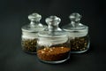 glass clear jars round bellied low for tea with lid on black textured background with custard black and green tea inside