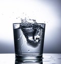 A glass of clear water. Ice falls and creates splashes Royalty Free Stock Photo