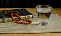 Glass of clear water, rosary and book of Quran. First drink, Muslim fast Eid al, Uraza