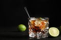 Glass of cocktail with cola, ice and cut lime on table against black background. Royalty Free Stock Photo