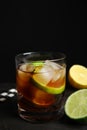 Glass of cocktail with cola, ice and cut lime on table against black background Royalty Free Stock Photo