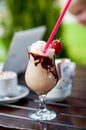 A glass of cocktail milkshake frappe decorated with strawberry and chocklate on the wooden table with laptot Royalty Free Stock Photo