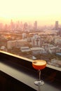 Glass of cocktail on the rooftop bar`s table with aerial urban view in background