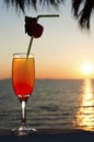 Glass with cocktail and a straw against blue sea, sky and sunset Royalty Free Stock Photo