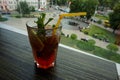 A glass with a cocktail on a table with a panorama overlooking the city.