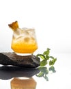 A glass with a cocktail of white rum and pineapple stands on a gray stone on a white background. Close-up