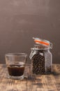 Glass of cofee with cofee beans. Selective focus. Cup of black coffee in a glass and grains in a glass jar on a wooden table Royalty Free Stock Photo