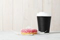Glass with coffee and sweet tasty donut on a light background