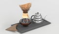 Glass coffeemaker with paper filter and silver drip kettle on black tray, angle view. Clear receptacle with wood collar