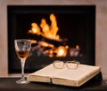 Glass of cognac and book by the fireplace Royalty Free Stock Photo