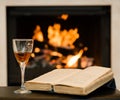 Glass of cognac and book by the fireplace Royalty Free Stock Photo