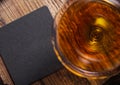 Glass of cognac brandy drink with black coaster on top of wooden