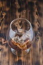 Glass of cognac with ice cubes on a wooden table/Glass of cognac with ice cubes on a wooden bar. Beautiful glass Royalty Free Stock Photo