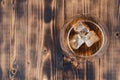 Glass of cognac with ice cubes on a wooden table/Glass of cognac with ice cubes on a wooden bar. Top view, copyspace Royalty Free Stock Photo
