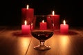 Glass of cognac and red candle on a wooden background Royalty Free Stock Photo