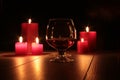Glass of cognac and red candle on a wooden background Royalty Free Stock Photo
