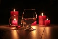Glass of cognac and red candle on a wooden background Royalty Free Stock Photo