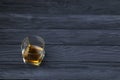 Glass with cognac or whisky alcohol drink on black wooden table close up with copy space for text. Elite alcohol drinking or
