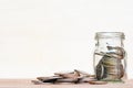 Glass of coin and spread coin on floor on vintage blurred background - Saving money concept. Royalty Free Stock Photo