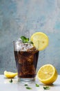 glass of cola or coke with ice cubes, lemon slices and peppermint garnish against a blue vintage wall Royalty Free Stock Photo