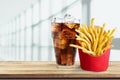 Glass of cola with ice cubes and fries isolated on