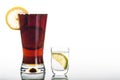 Glass of cola with sliced lemon and shot of vodka