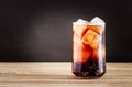 Glass of cola soft drink with ice cubes on wooden table and black background. Royalty Free Stock Photo