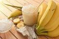 Glass of cold banana drink with ice on wooden table