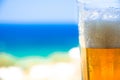 Glass of cold beer on blurred aegean sea background.