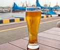 A glass of cold beer standing on a red table against the backdrop of a yacht Royalty Free Stock Photo