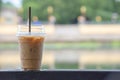 Glass of cold espresso coffee on the steel rod Background blurry tree and water