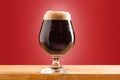 Glass of cold frothy dark beer on an old wooden table Royalty Free Stock Photo