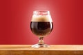 Glass of cold frothy dark beer on an old wooden table Royalty Free Stock Photo