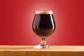 Glass of cold frothy dark beer on an old wooden table