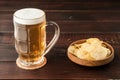 Glass of cold frothy lager beer and potato chips plate on wooden Royalty Free Stock Photo