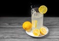 A glass of cold lemonade with a falling lemon and lemons around a ceramic plate Royalty Free Stock Photo
