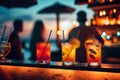 Glasses of cocktails on the table of a beach bar. Sunset, blurry people. Summer holidays travel. Generative AI. Royalty Free Stock Photo