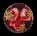 Glass with a cold red drink and with strawberries in ice cubes isolated on a black background Royalty Free Stock Photo